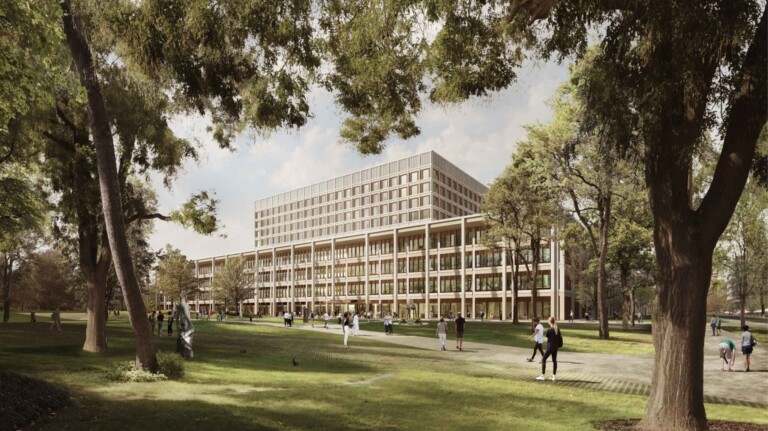 Moderner mehrstöckiger Bürogebäudekomplex mit großen Fenstern, umgeben von einem Park mit vielen Bäumen, grünen Rasenflächen und mehreren Personen, die sich auf Gehwegen und im Freien bewegen.