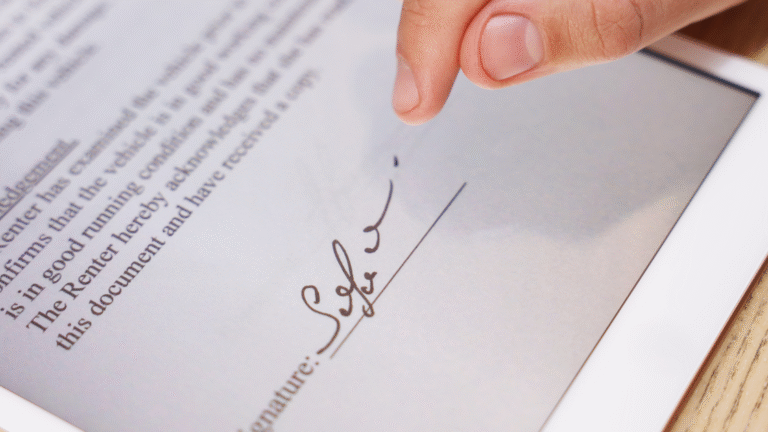 Finger berührt ein digitales Tablet mit einem Dokument, auf dem eine Unterschrift zu sehen ist.