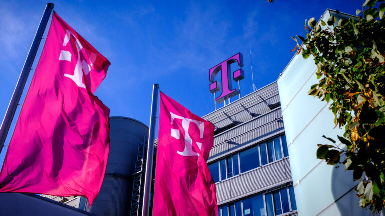 Drapeaux magenta de Telekom et logo T sur le toit du siège de Deutsche Telekom, sur fond de ciel bleu